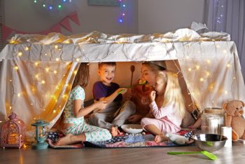 A fort with kids inside. Fort was built using a table, sheets, and lights